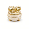 Cutie Bijuterii Rotundă Alb-Crem 5x5 cm cu Fundă Aurie și Piciorușe